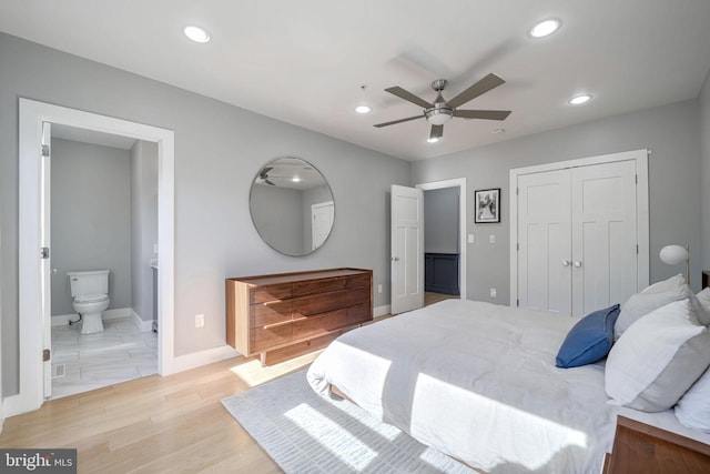 bedroom with a closet, light hardwood / wood-style floors, ensuite bathroom, and ceiling fan