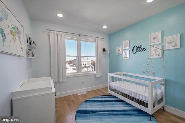 bedroom featuring light hardwood / wood-style flooring and a nursery area