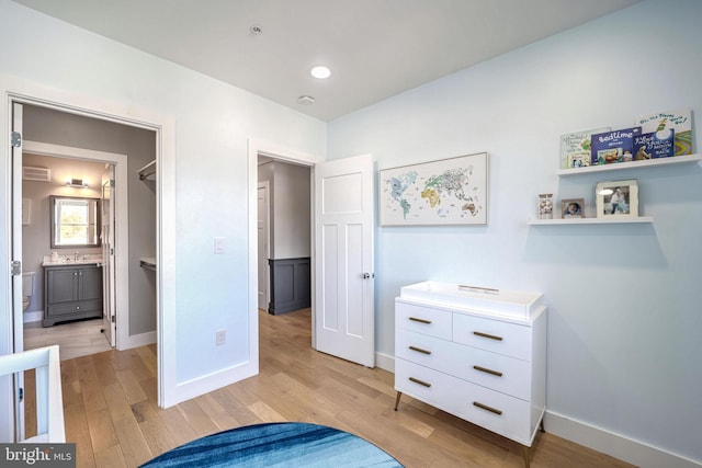 bedroom featuring ensuite bathroom and light wood-type flooring