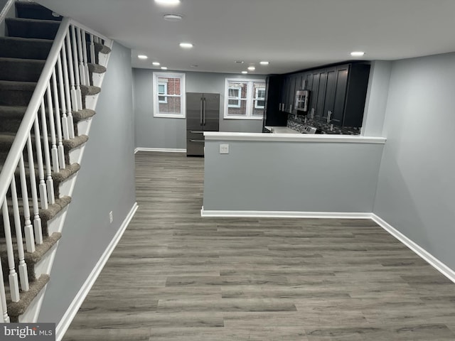 kitchen with appliances with stainless steel finishes, kitchen peninsula, dark wood-type flooring, and backsplash