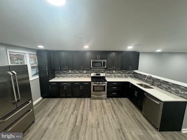 kitchen featuring light hardwood / wood-style flooring, decorative backsplash, stainless steel appliances, and sink