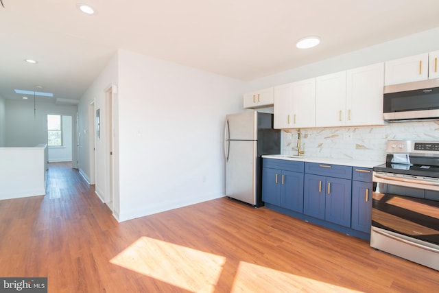 kitchen with appliances with stainless steel finishes, light hardwood / wood-style flooring, white cabinets, and blue cabinets