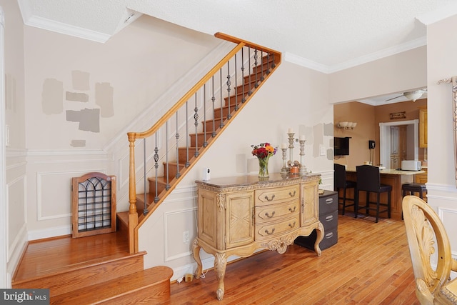 staircase with ornamental molding, hardwood / wood-style floors, and a textured ceiling