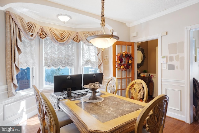 dining area with a textured ceiling, light hardwood / wood-style flooring, and ornamental molding