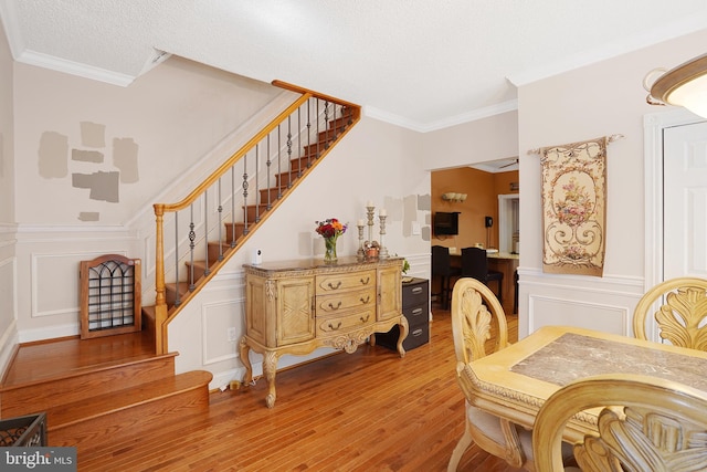 dining space with wood-type flooring, a textured ceiling, ornate columns, and ornamental molding