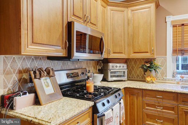 kitchen featuring tasteful backsplash, light stone countertops, and appliances with stainless steel finishes