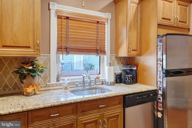 kitchen featuring light stone counters, sink, backsplash, and appliances with stainless steel finishes