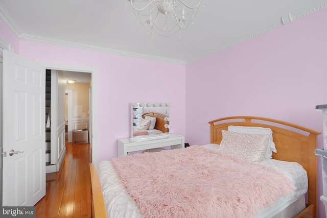 bedroom featuring ornamental molding, light hardwood / wood-style floors, and a notable chandelier