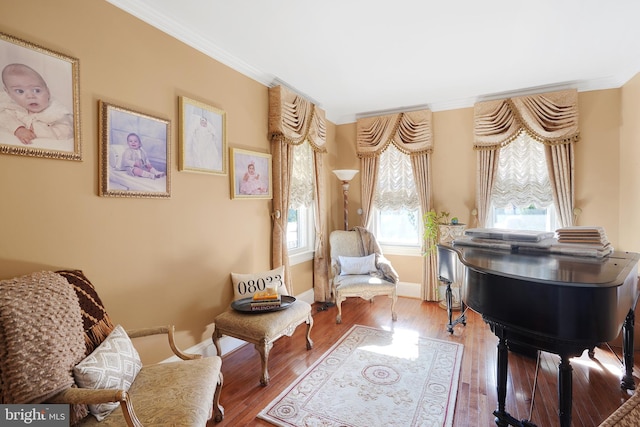 living area with hardwood / wood-style floors, a wealth of natural light, and crown molding