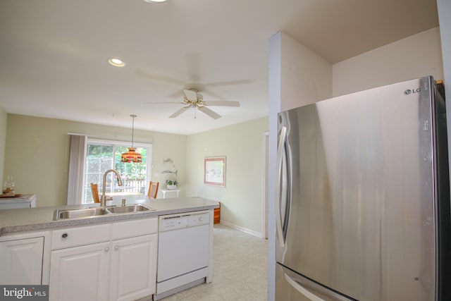 kitchen with pendant lighting, dishwasher, sink, stainless steel refrigerator, and white cabinetry