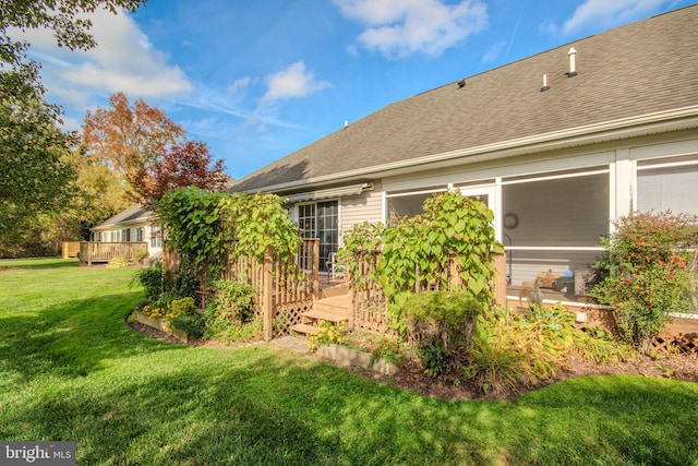 rear view of property featuring a wooden deck and a lawn