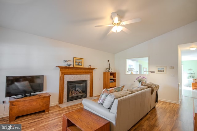 living room featuring ceiling fan, light hardwood / wood-style flooring, and vaulted ceiling