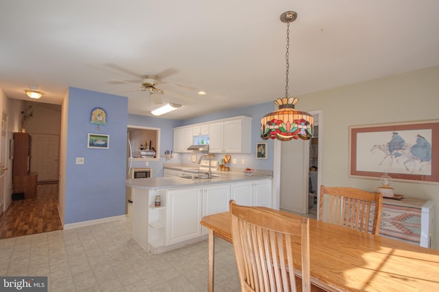 kitchen featuring sink, kitchen peninsula, ceiling fan, decorative light fixtures, and white cabinets