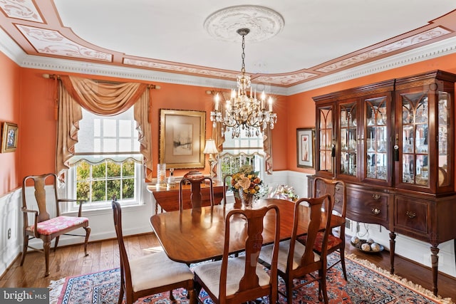 dining area featuring hardwood / wood-style flooring, ornamental molding, and a chandelier