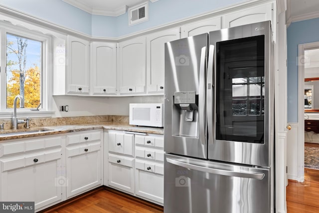 kitchen with stainless steel refrigerator with ice dispenser, white cabinets, sink, and wood-type flooring