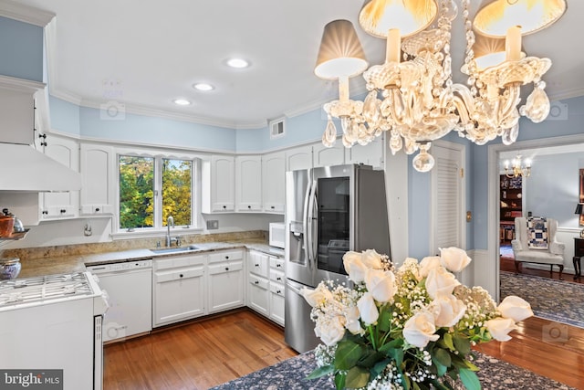 kitchen featuring hardwood / wood-style flooring, crown molding, sink, white cabinets, and white appliances