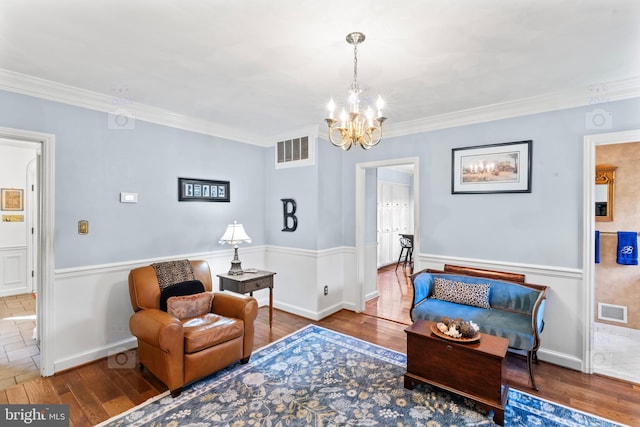 sitting room with ornamental molding, hardwood / wood-style floors, and a chandelier