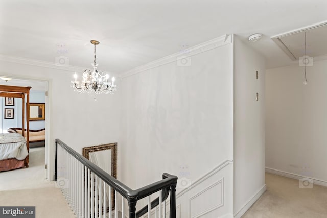 hallway with a notable chandelier, crown molding, and light carpet