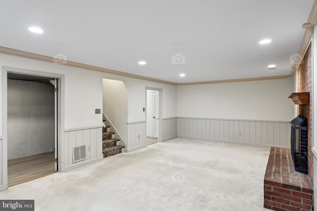 basement featuring ornamental molding, a fireplace, and carpet floors