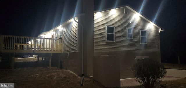 property exterior at night featuring a wooden deck