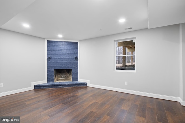 unfurnished living room featuring dark hardwood / wood-style floors and a brick fireplace