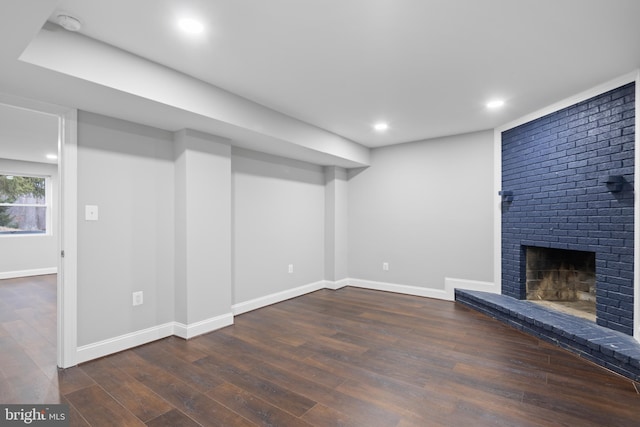 basement with dark wood-type flooring and a brick fireplace