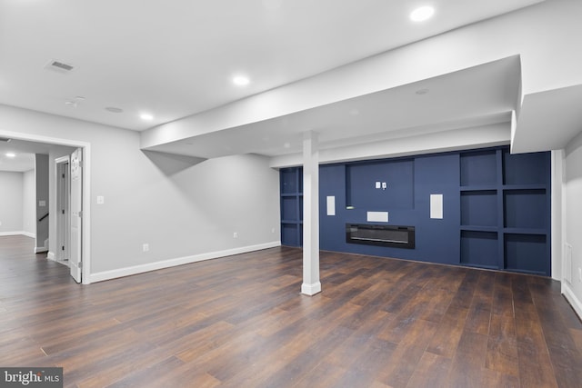 basement featuring built in shelves and dark wood-type flooring