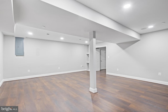 basement with dark wood-type flooring and electric panel