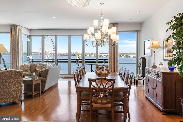 dining space with hardwood / wood-style floors, a water view, and an inviting chandelier