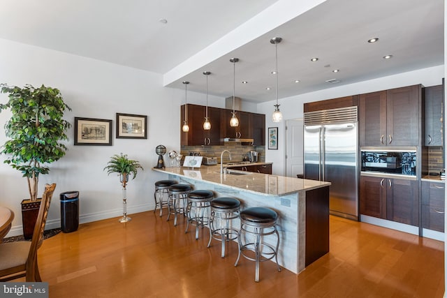 143 Waterfront St Unit 502, National Harbor, MD 20745 - kitchen featuring stainless steel built in refrigerator, a breakfast bar, decorative backsplash, light wood-style flooring, and recessed lighting