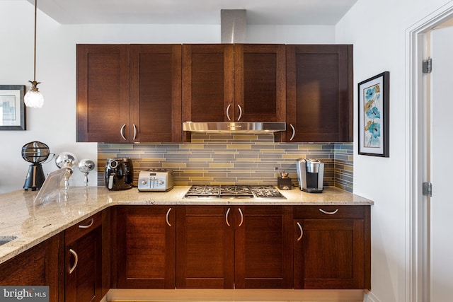 kitchen with stainless steel gas cooktop, hanging light fixtures, tasteful backsplash, and light stone countertops