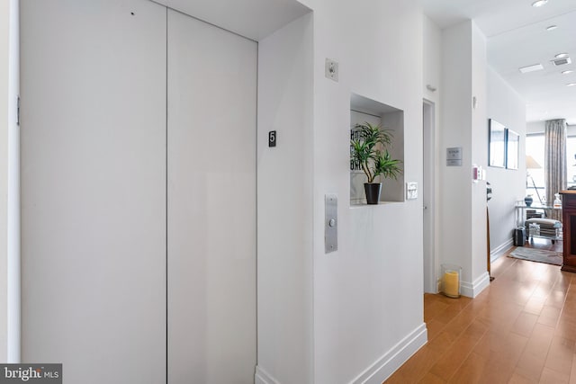 143 Waterfront St Unit 502, National Harbor, MD 20745 - hall featuring elevator, baseboards, and light wood-style flooring