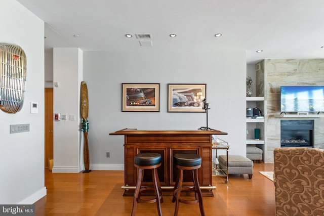 dining space with a tile fireplace and light hardwood / wood-style flooring