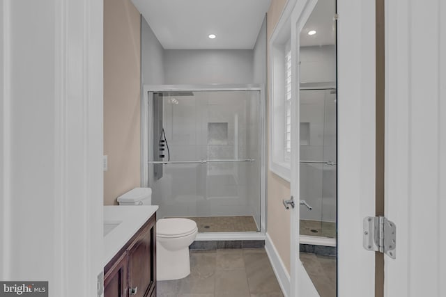 bathroom with toilet, walk in shower, vanity, and tile patterned flooring