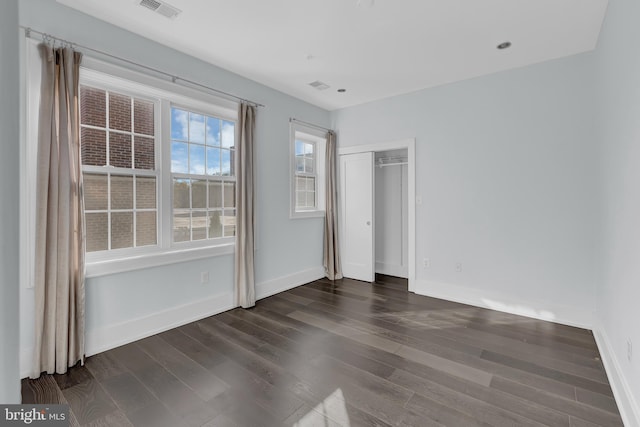 unfurnished bedroom featuring a closet and dark wood-type flooring