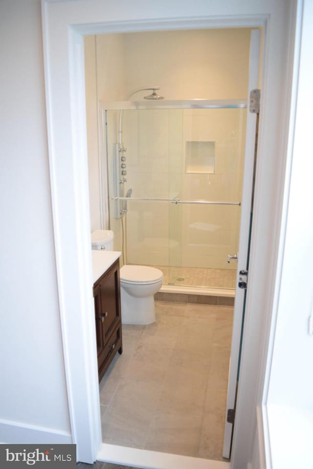 bathroom featuring toilet, a shower stall, and vanity