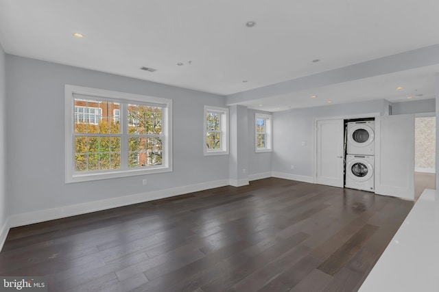 unfurnished living room with stacked washing maching and dryer and dark hardwood / wood-style flooring