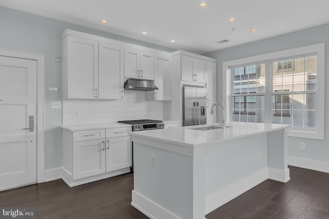 kitchen featuring dark hardwood / wood-style floors, an island with sink, stainless steel appliances, and white cabinetry