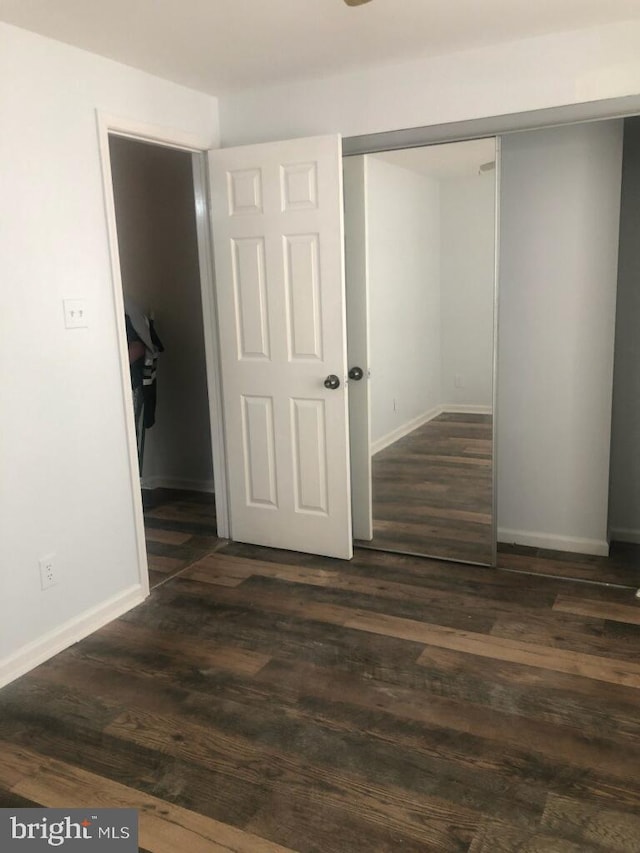 unfurnished bedroom with a closet and dark hardwood / wood-style flooring