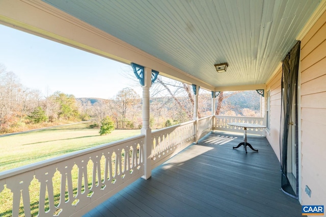 wooden terrace featuring covered porch and a lawn