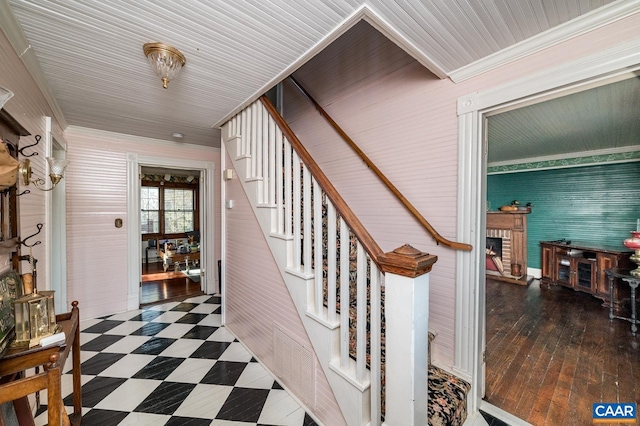 staircase with hardwood / wood-style floors and a brick fireplace