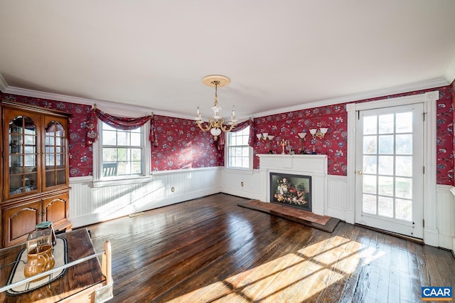 unfurnished living room with hardwood / wood-style flooring, ornamental molding, and a wealth of natural light