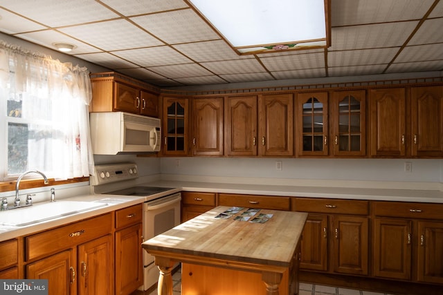 kitchen featuring butcher block counters, white appliances, sink, and a center island