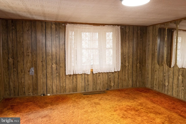 carpeted empty room featuring wooden walls