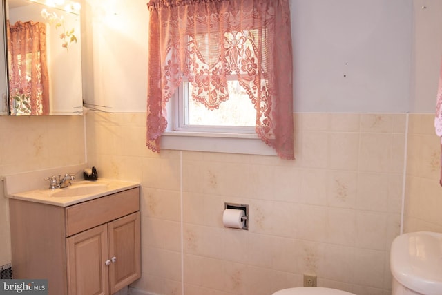 bathroom with toilet, vanity, and tile walls