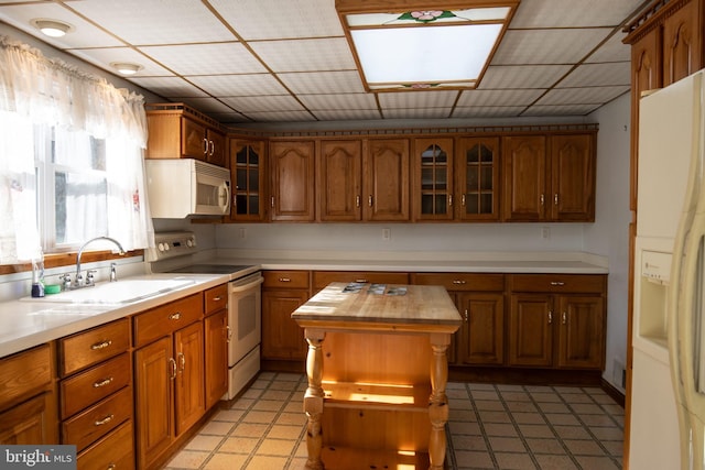 kitchen featuring a center island, sink, butcher block countertops, a skylight, and white appliances