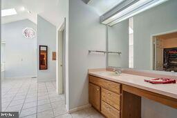 bathroom featuring tile patterned flooring, vanity, and lofted ceiling