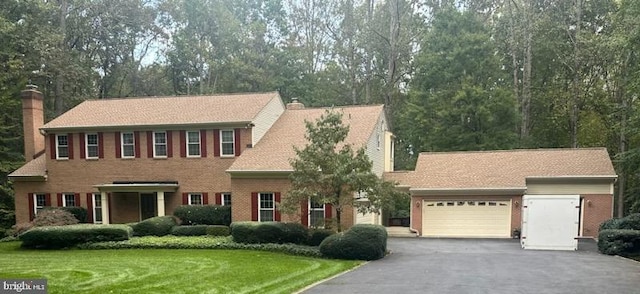 colonial home featuring a garage and a front lawn