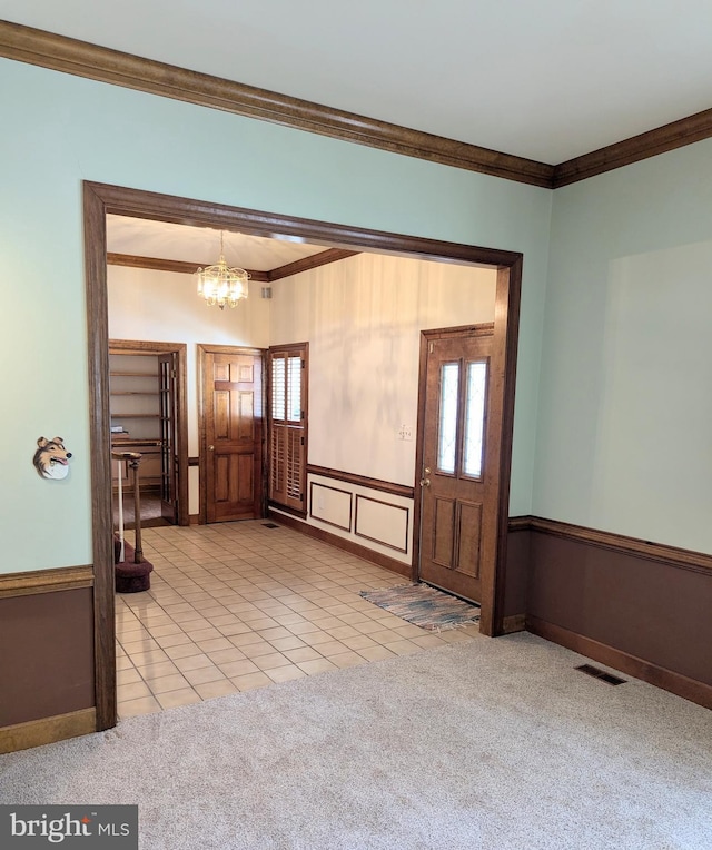 foyer with crown molding, light carpet, and a chandelier