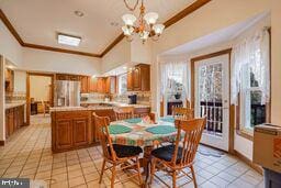 dining area with ornamental molding, vaulted ceiling, light tile patterned floors, and a notable chandelier